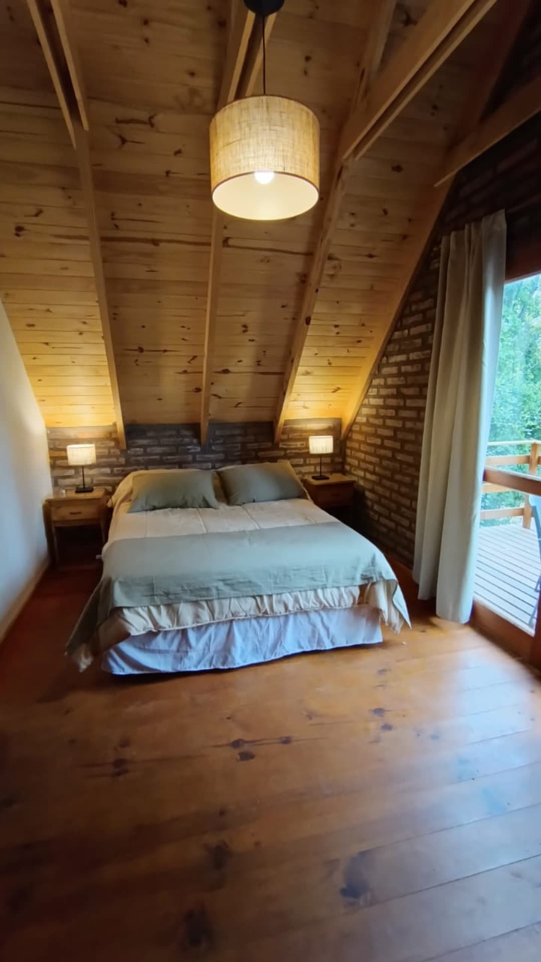 Dormitorio matrimonial con techo de madera y ladrillo